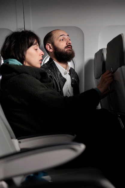 Free photo man and woman travelling on vacation by airplane transport, waiting to takeoff on commercial flight in economy class, going to voyage destination. international airways on aerial transportation.