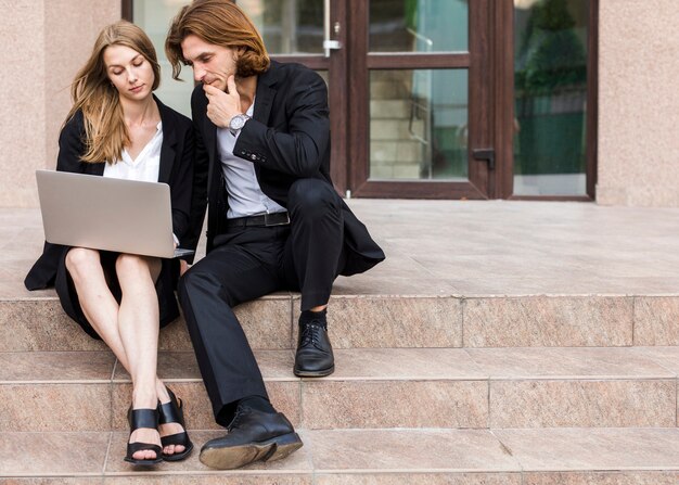 Man and woman using a laptop on stairs