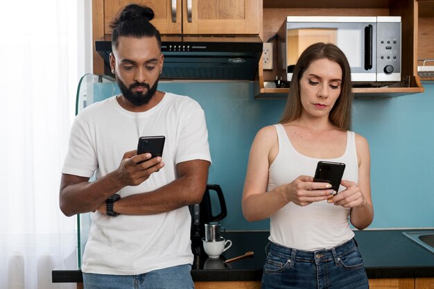 キッチンで携帯電話を使用している男性と女性