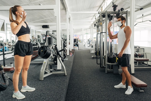 Free photo man and woman waving at each other at the gym