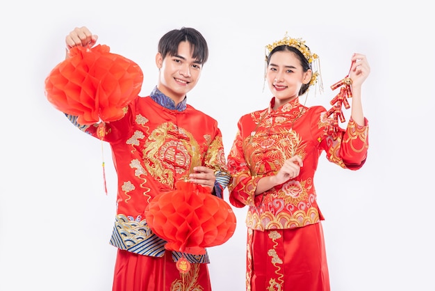 Free photo man and woman wear cheongsam suit celebrate chinese new year with red lamp and firecracker