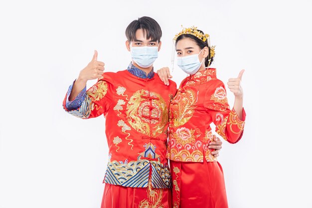 Man and woman wear Cheongsam suit and mask Thumbs up to event will be happened on chinese new year