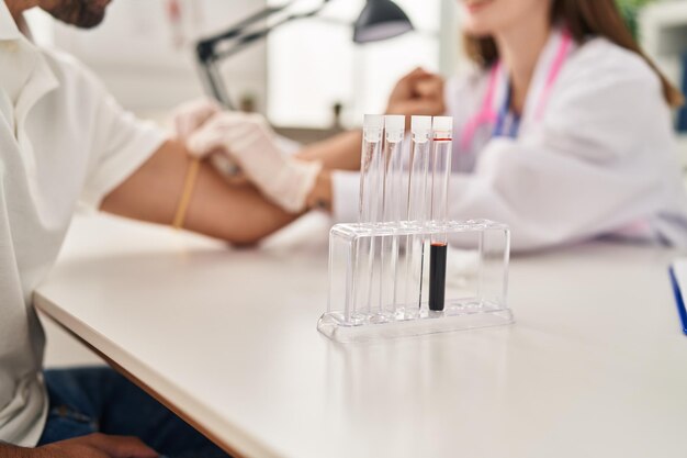 Man and woman wearing doctor uniform having blood analysis at clinic