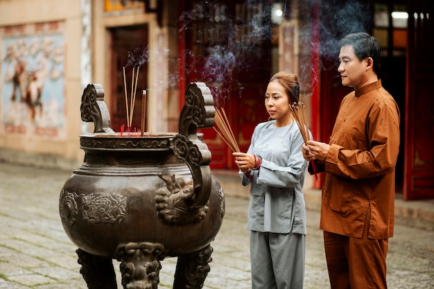 Free photo man and woman with incense at the temple