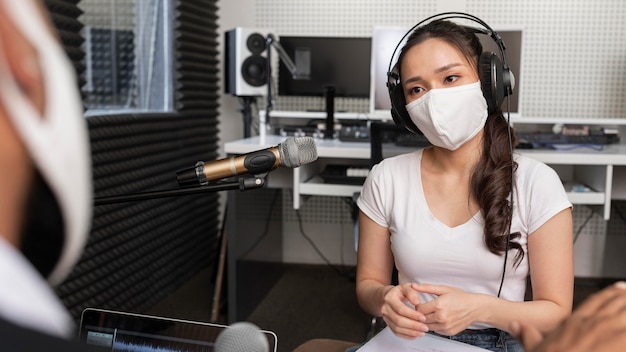 Man and woman with medical mask having a discussion at a radio station