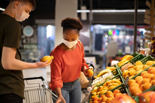 man and woman with medical masks out grocery shopping with shopping cart