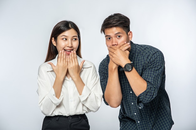 Free photo the man and woman wore shirts and covered their mouths with their hands in shock