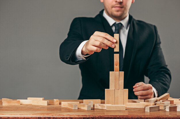 Man and wooden cubes on table. management concept