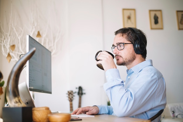 Man working on computer and drinking