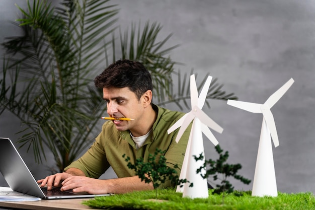 Man working on an eco-friendly wind power project with wind turbines and laptop