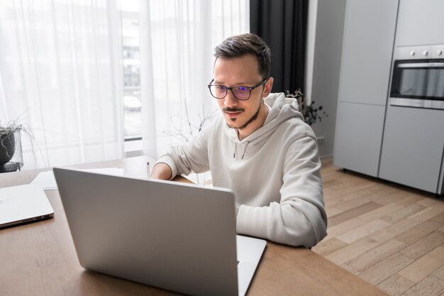 Человек, работающий из дома за столом с ноутбуком