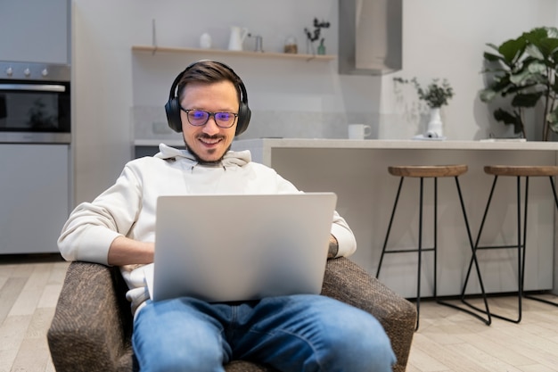 Foto gratuita uomo che lavora dalla cucina di casa con il laptop