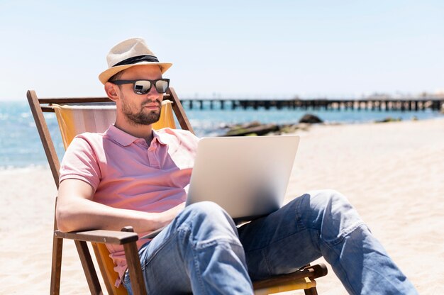 Человек работает на ноутбуке на пляже