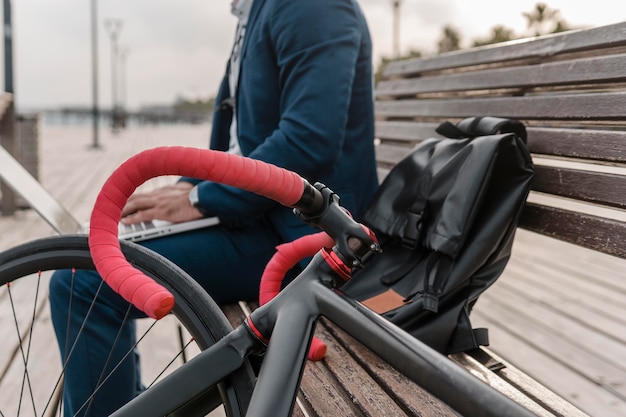 Man working on a laptop next to his bike outdoors