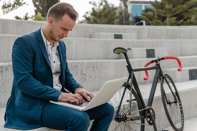 屋外で自転車の横にあるラップトップで作業している男性