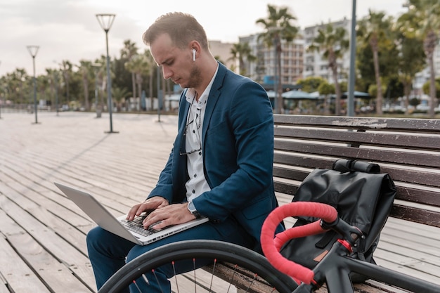 Man working on a laptop next to his bike outside