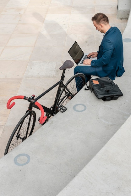 Man working on laptop next to his bike