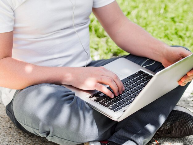 man working on laptop outdoors with earphones on