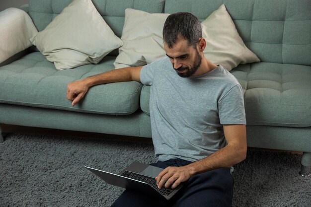 Man working on laptop next to sofa