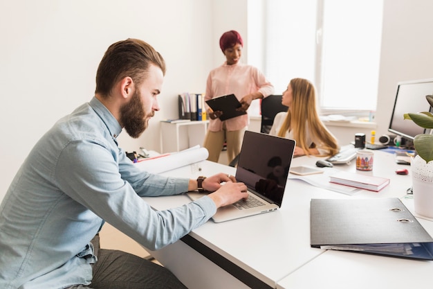 Man working near chatting colleagues