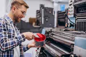 Free photo man working in printing house with paper and paints