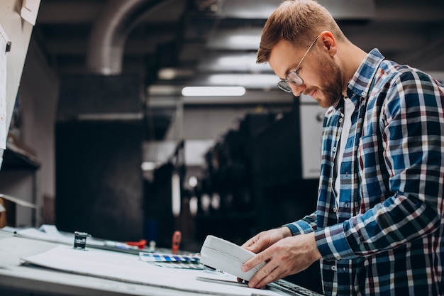 Man working in printing house with paper and paints