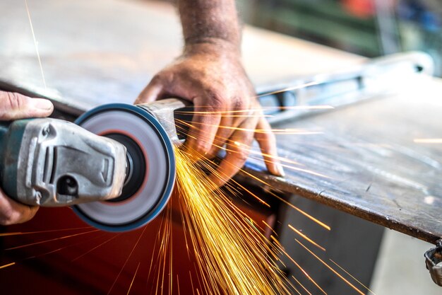 Man working with an angular grinder with sparkles from it