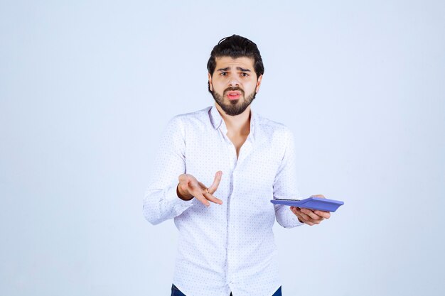 Man working with calculator looks confused and thoughtful.