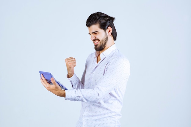 Man working with calculator looks successful and satisfied.