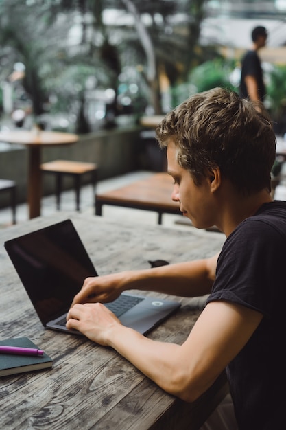 Free photo man working with a laptop in a cafe on a wooden table