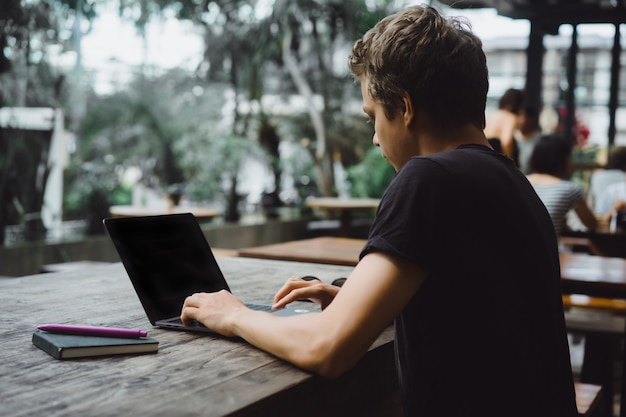 man working with a laptop in a cafe on a wooden table