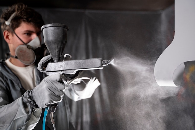 Foto gratuita uomo che lavora con il colpo medio della pistola della vernice