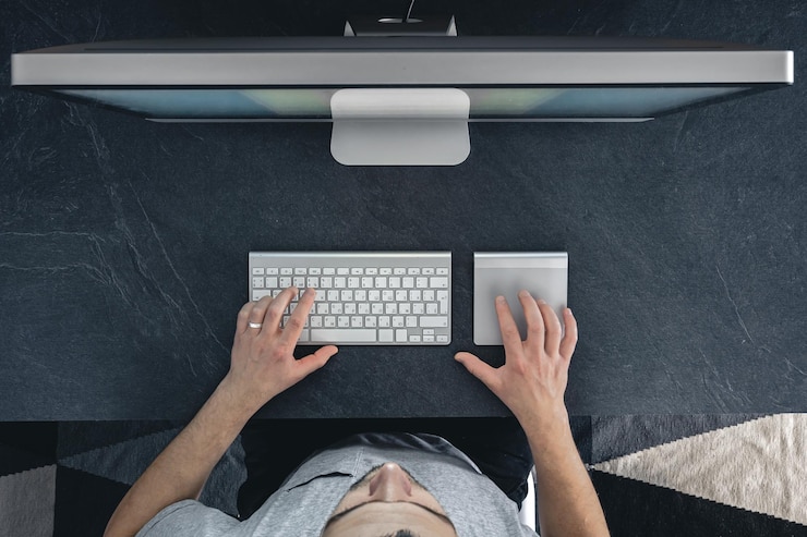 Free Photo a man works at a computer top view desktop computer on a table