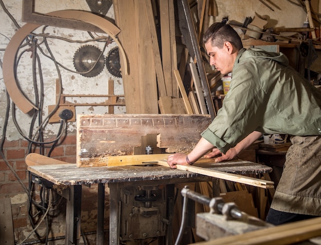 男は木製品の製造で機械で作業します