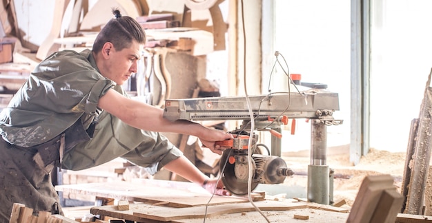 男は木製の製品で機械で作業します