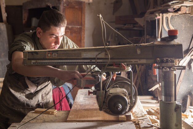 a man works on the machine with the wooden product