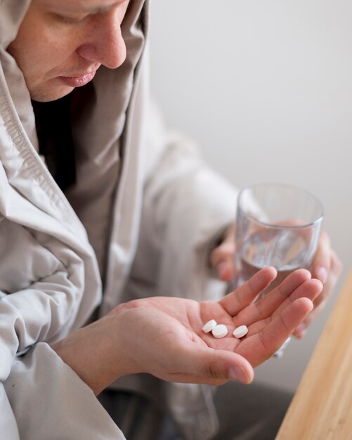 Man wrapped in a blanket taking his pills