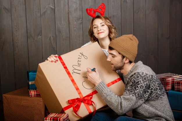 女友達と座っているギフトボックスメリークリスマスに書いているその男