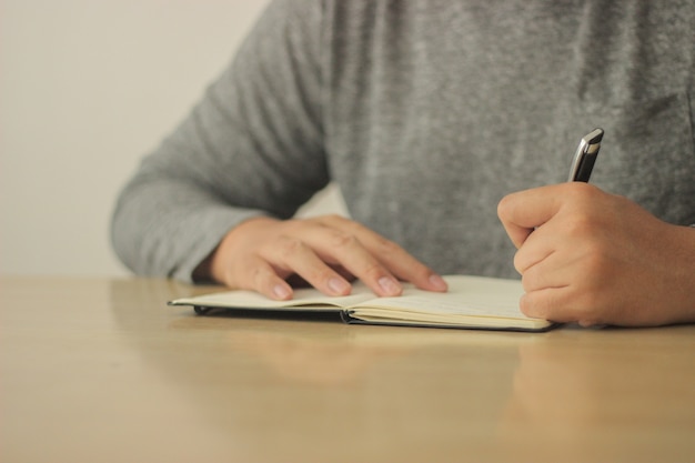 Man writing on his notebook with a black pen