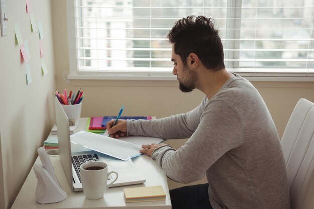 Бесплатное фото Человек, пишущий на документе, сидя за столом