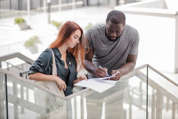 Man writing in papers helping to woman