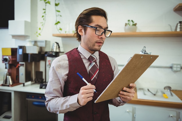 Free photo man writing with pen on clipboard