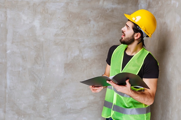 Man in yellow helmet and gear looking to the repaired wall and feeling satisfied