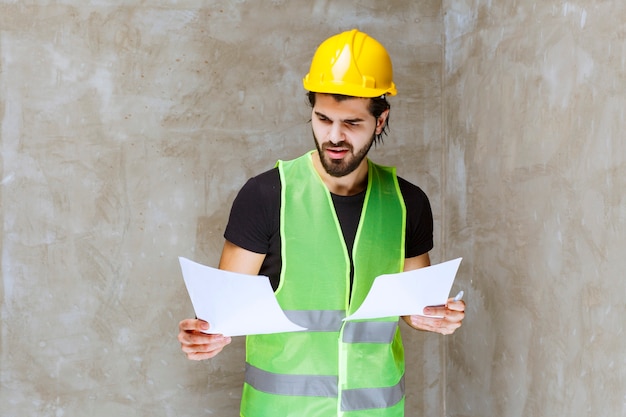 Free photo man in yellow helmet and gear verifying the project sheets