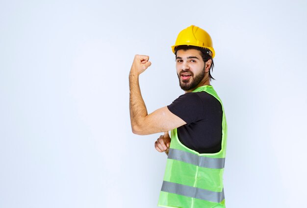 Man in yellow helmet showing his arm muscles.