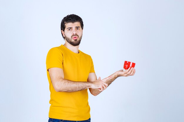 Man in yellow shirt holding a red cup and thinking.