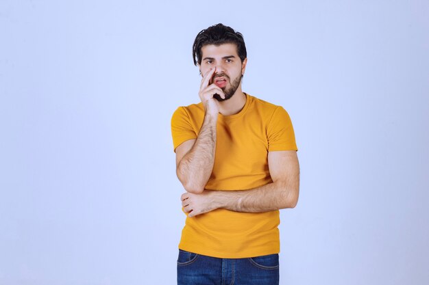 Man in yellow shirt looks doubtful and thinking. 