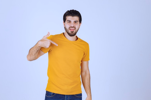 Man in yellow shirt pointing at himself.