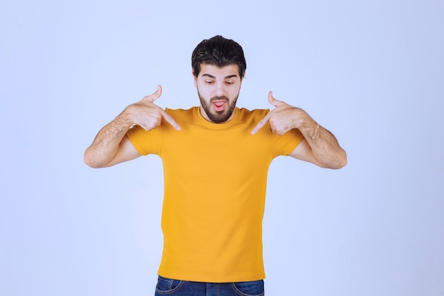 Free photo man in yellow shirt pointing at himself.