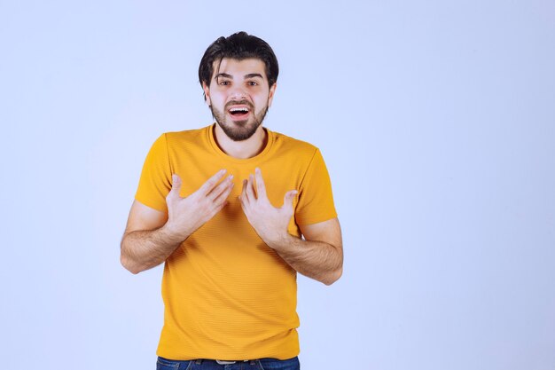 Man in yellow shirt pointing at himself. 